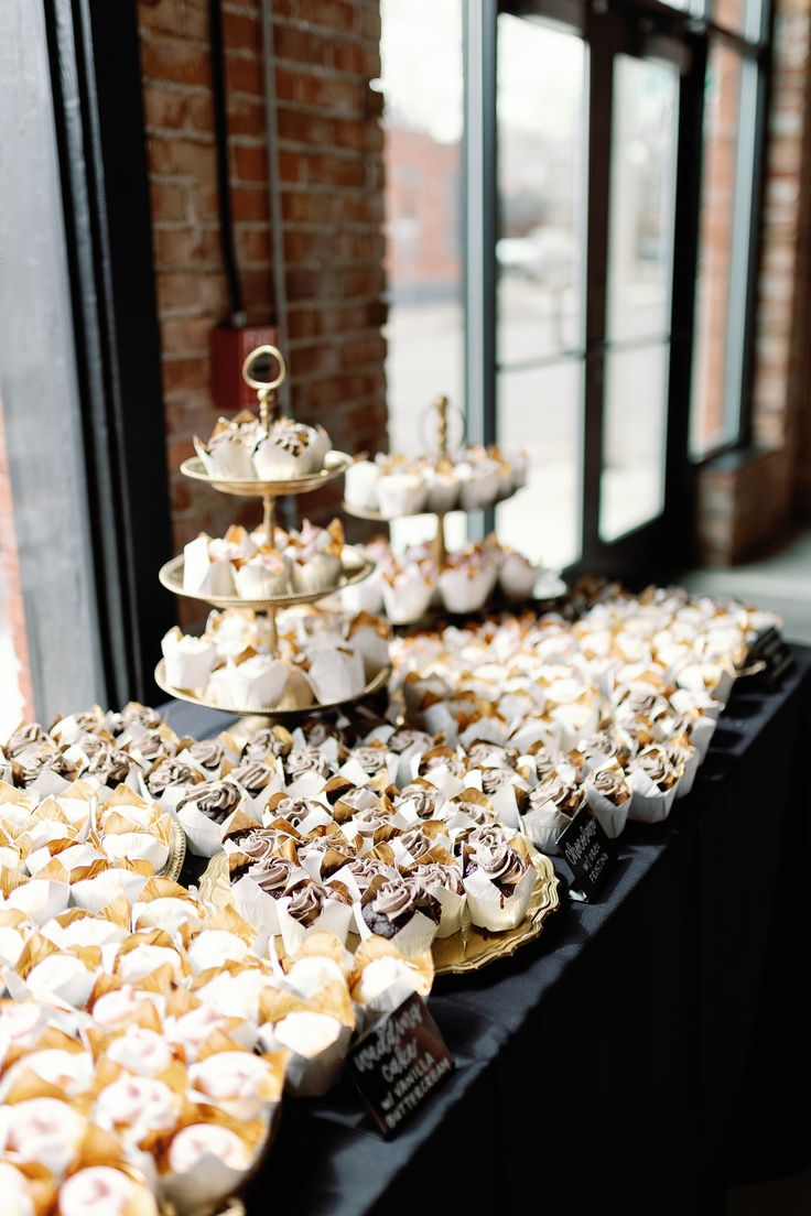 a table topped with lots of cupcakes covered in frosting