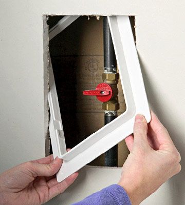 a person holding a red wrench in front of a hole in the wall that is being installed