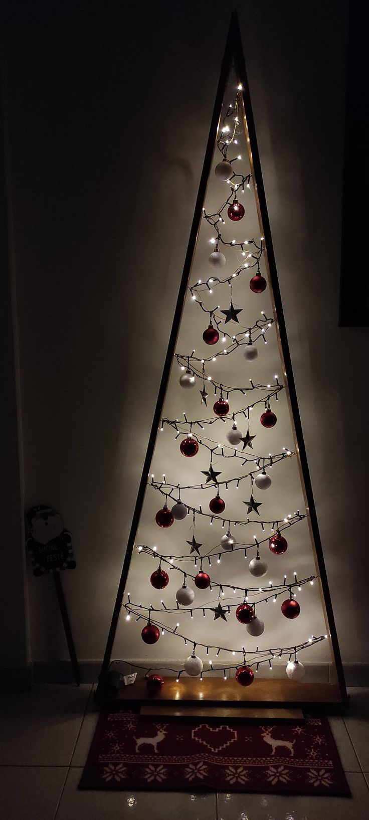 a lighted christmas tree in the corner of a room with a rug on the floor