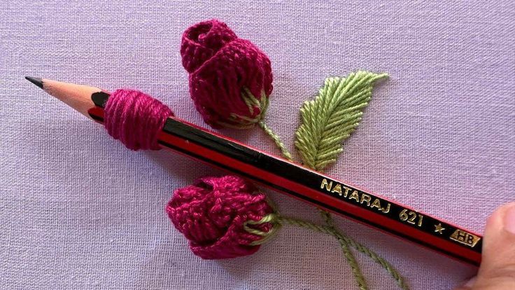 a crochet flower and pencil with yarn on it