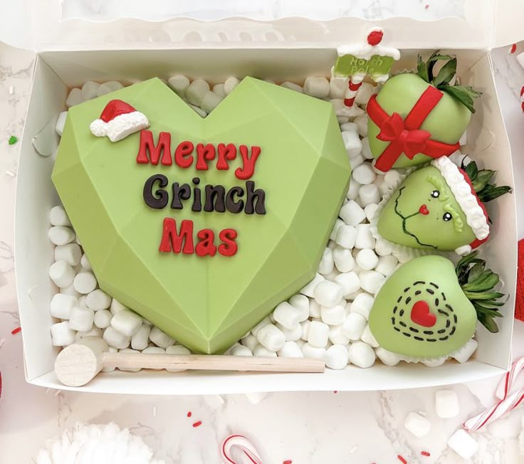 a green heart shaped cake sitting on top of white rocks next to other holiday decorations