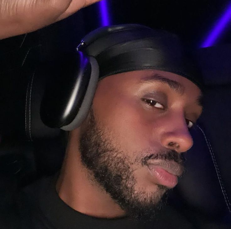 a man with headphones on his ears in the back seat of a car at night