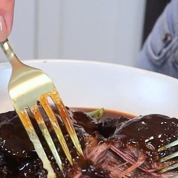 a person is holding a fork over a bowl of food with meat and broth