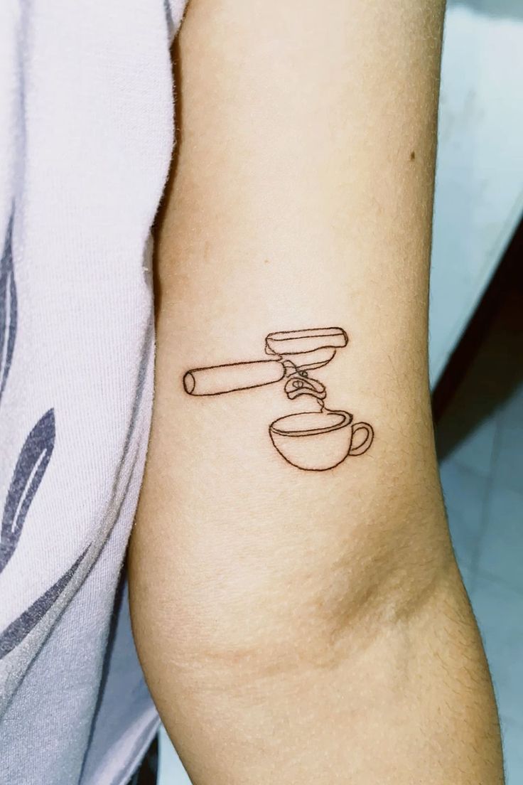 a person with a tattoo on their arm holding a coffee cup and a saucer