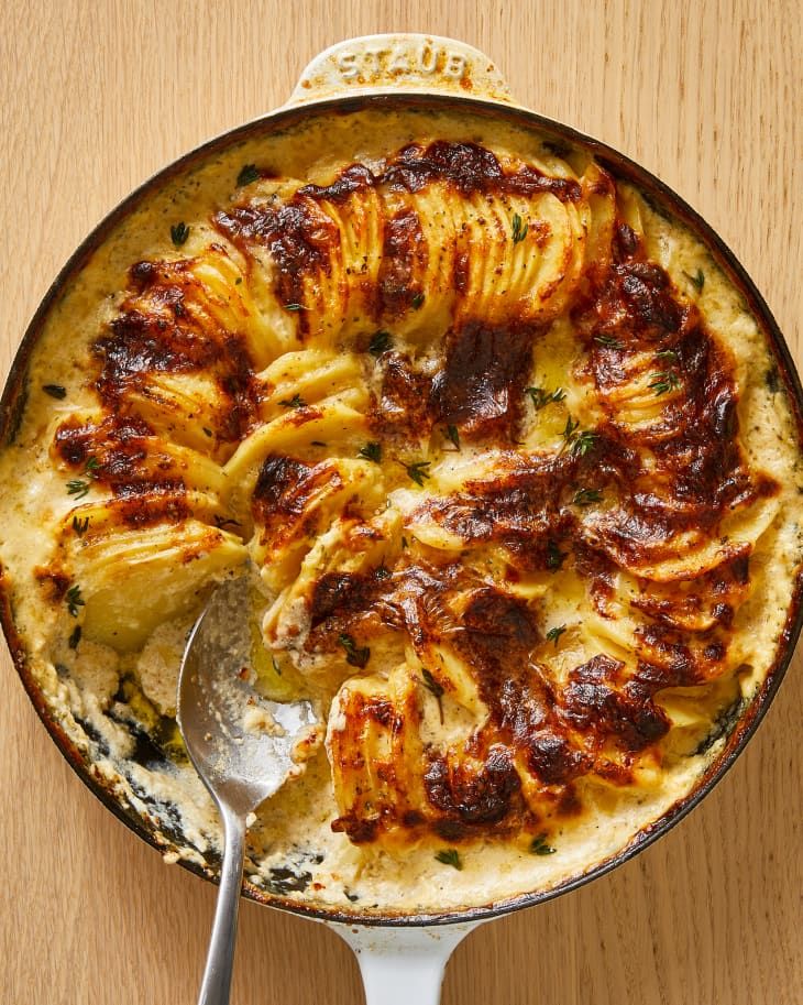 a casserole dish filled with pasta and sauce on a wooden table top next to a spoon