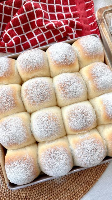 a pan filled with powdered sugar rolls on top of a table next to a red and white towel