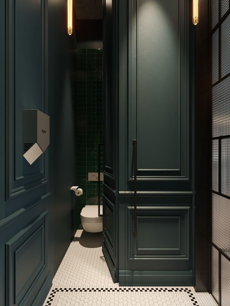 a bathroom with black and white tile flooring and dark green cabinets, along with a toilet in the corner