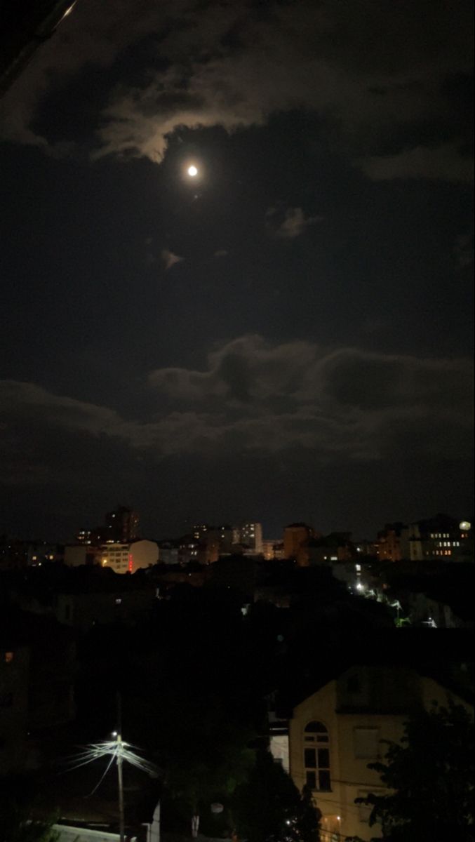 the full moon is seen above some buildings