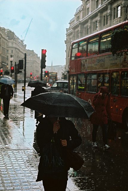 black and white photograph of people walking in the rain with umbrellas