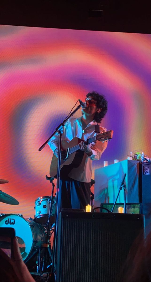 a man standing on top of a stage holding a guitar