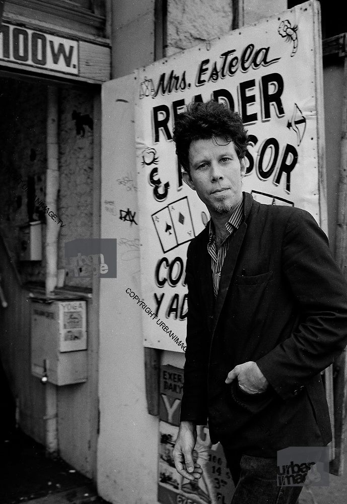 black and white photograph of a man standing in front of a building with posters on it