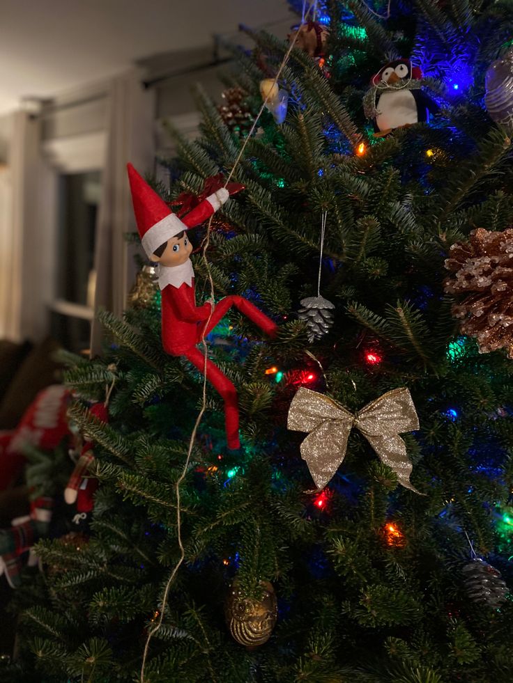 a christmas tree with an elf on top and other ornaments hanging from it's branches