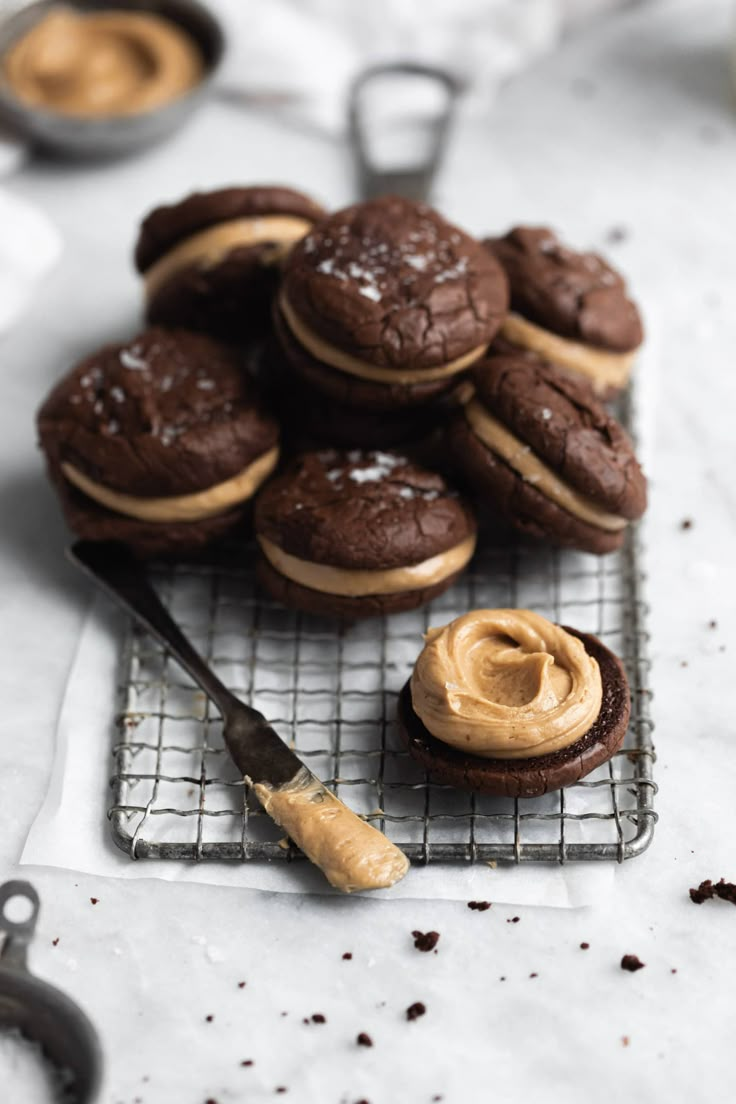 chocolate cookies with peanut butter frosting on a cooling rack next to cookie cutters