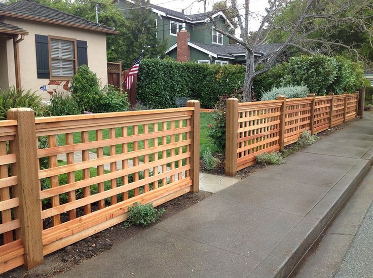 a wooden fence next to a sidewalk in front of a house