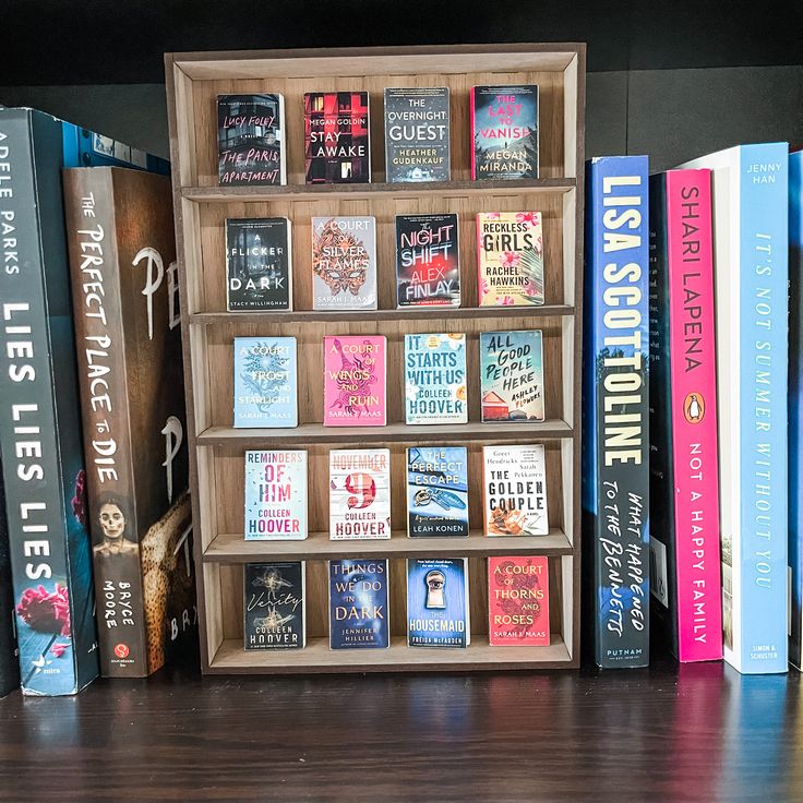 a book shelf filled with lots of books on top of a hard wood floor next to a wall