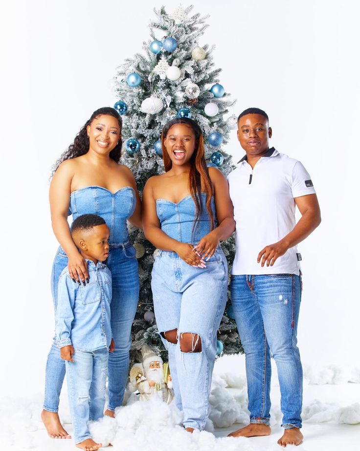 a family poses in front of a christmas tree