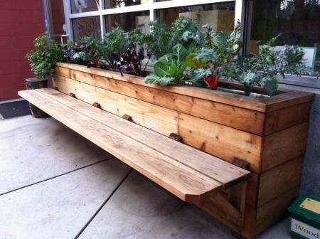 a wooden bench sitting next to a window filled with plants