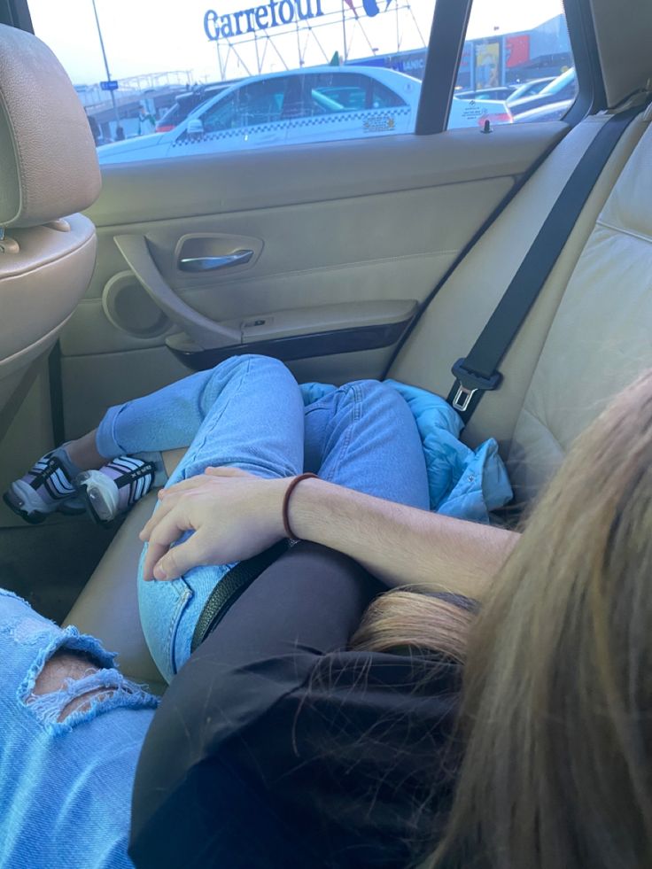 a person sleeping in the back seat of a car with their head on someone's lap