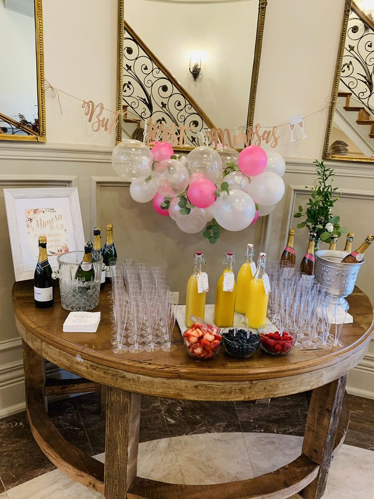 a wooden table topped with lots of drinks and balloons in front of a mirror on the wall