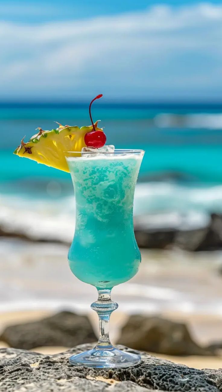 a blue drink sitting on top of a rock next to the ocean