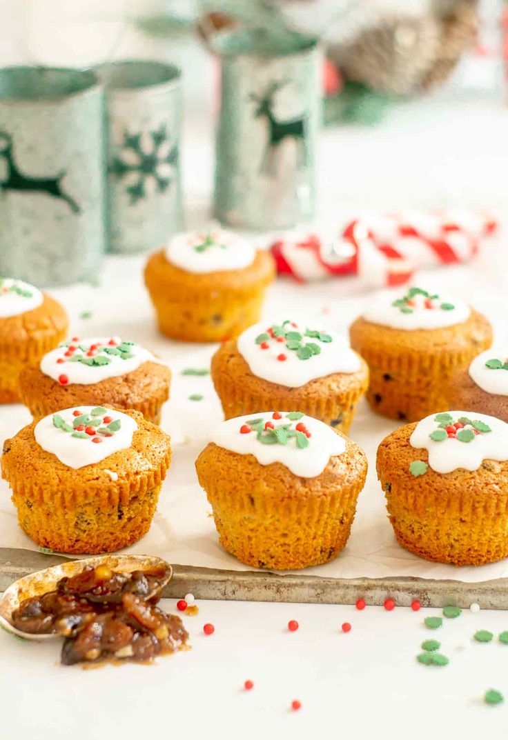 christmas cupcakes with white frosting and sprinkles on a tray