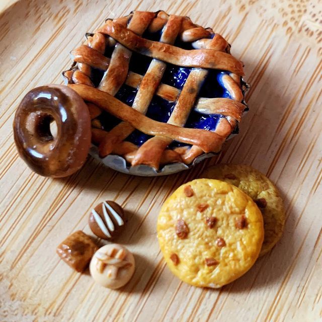 an assortment of pastries are arranged on a wooden table with a pie and chocolates