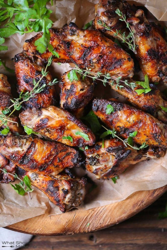 grilled chicken wings with herbs and parsley on a wooden platter, ready to be served