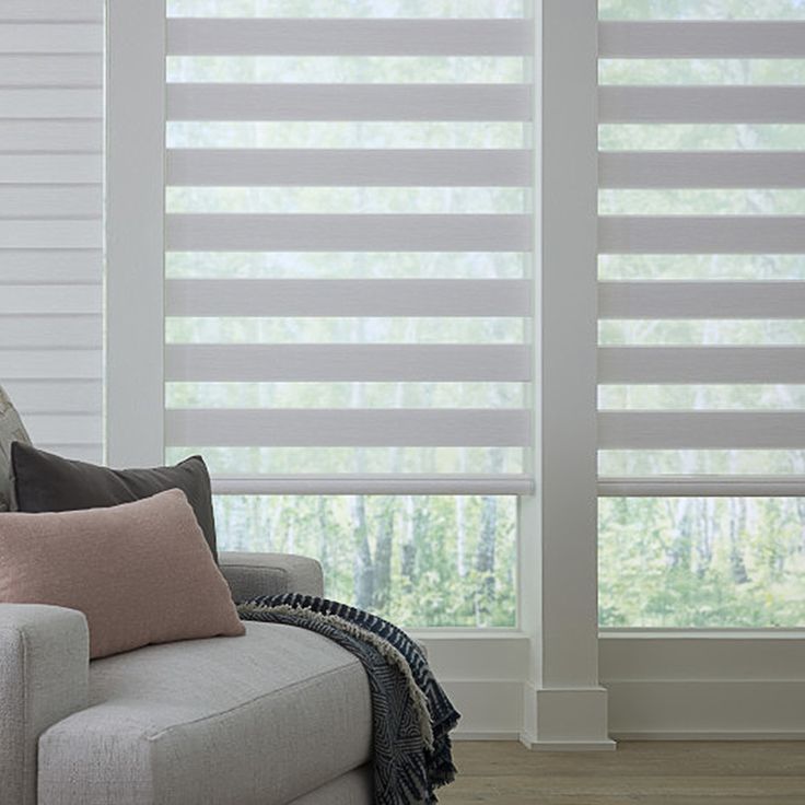 a living room with white blinds and pillows