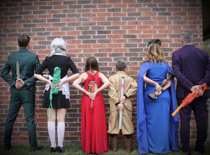 several people in costumes are standing against a brick wall with their backs to the camera