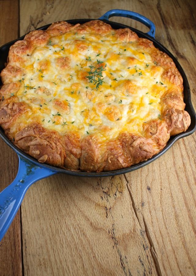 a cheesy casserole in a cast iron skillet on a wooden table