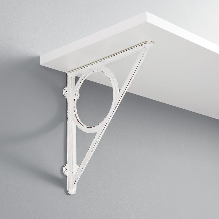 a white shelf with a triangle shaped object on it's side and a circular hole in the middle