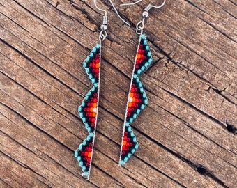 two pairs of beaded earrings sitting on top of a wooden table