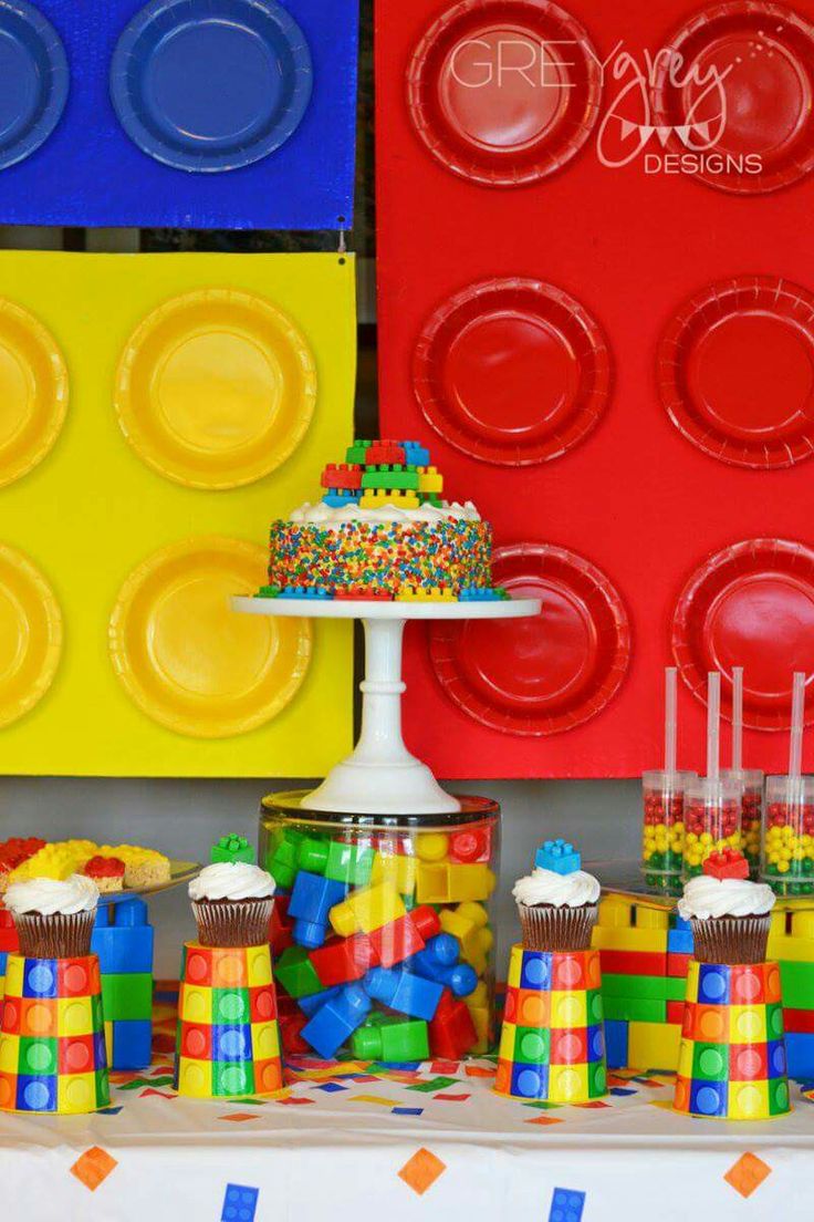 a table topped with cupcakes and cake next to lego wall paper plates on top of it