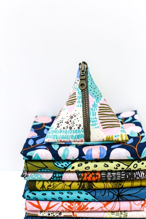 a stack of folded fabric with a zipper in the middle and an image of a sailboat on top