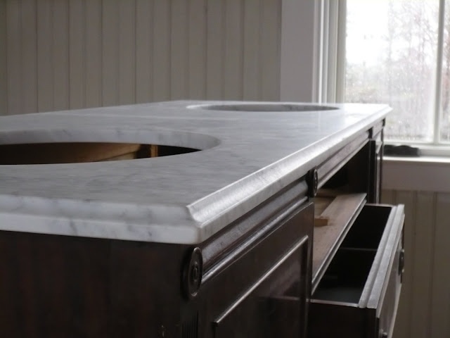 a marble counter top in front of a window with an open drawer on the bottom