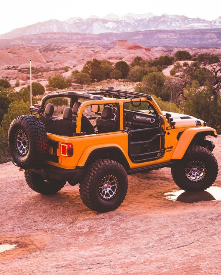 a yellow jeep parked on top of a dirt field