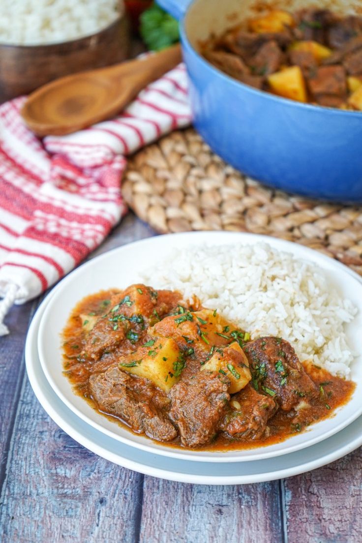 a white plate topped with meat and rice next to a blue bowl filled with rice