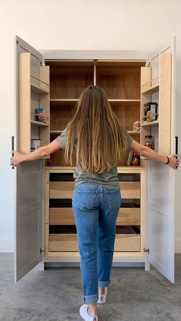 a woman standing in front of an open cabinet