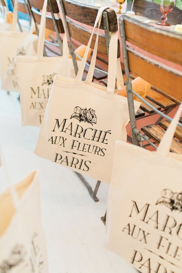 many bags are hanging from the side of a bench in front of a table with other items on it