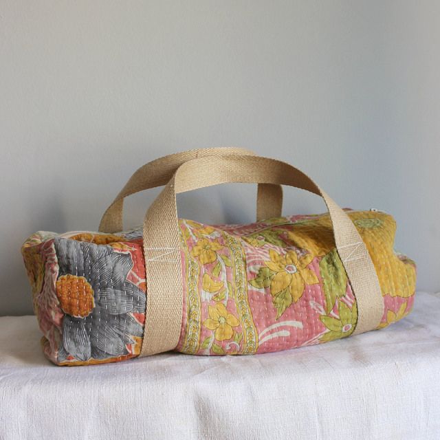 a colorful floral bag sitting on top of a white tablecloth covered bed next to a gray wall