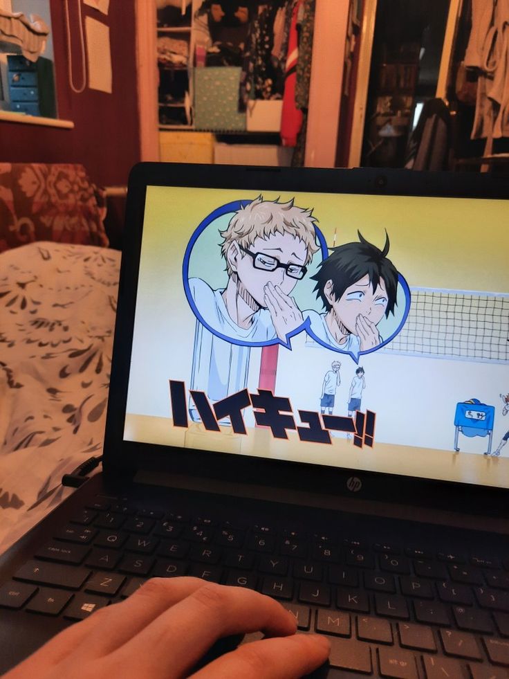 a person using a laptop computer with an anime character on the screen in front of them