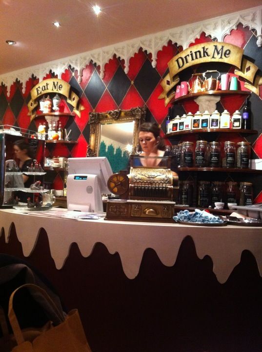 a woman behind a counter in a restaurant with red and black checkered wallpaper