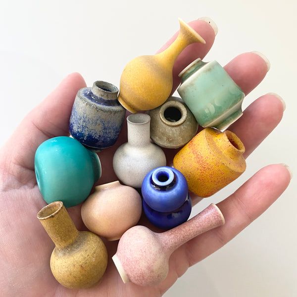 a hand holding several different colored vases in it's palm