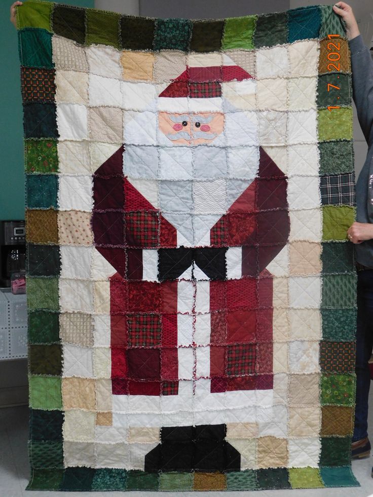 a woman holding up a quilt made to look like santa