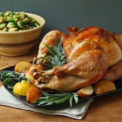 a roasted turkey on a platter with apples, oranges and other vegetables