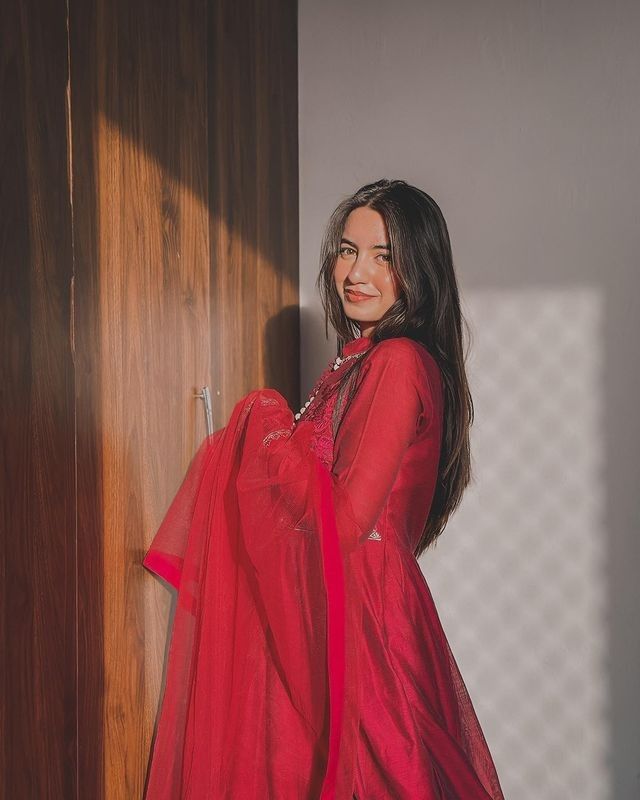 a woman in a red dress standing next to a wooden door