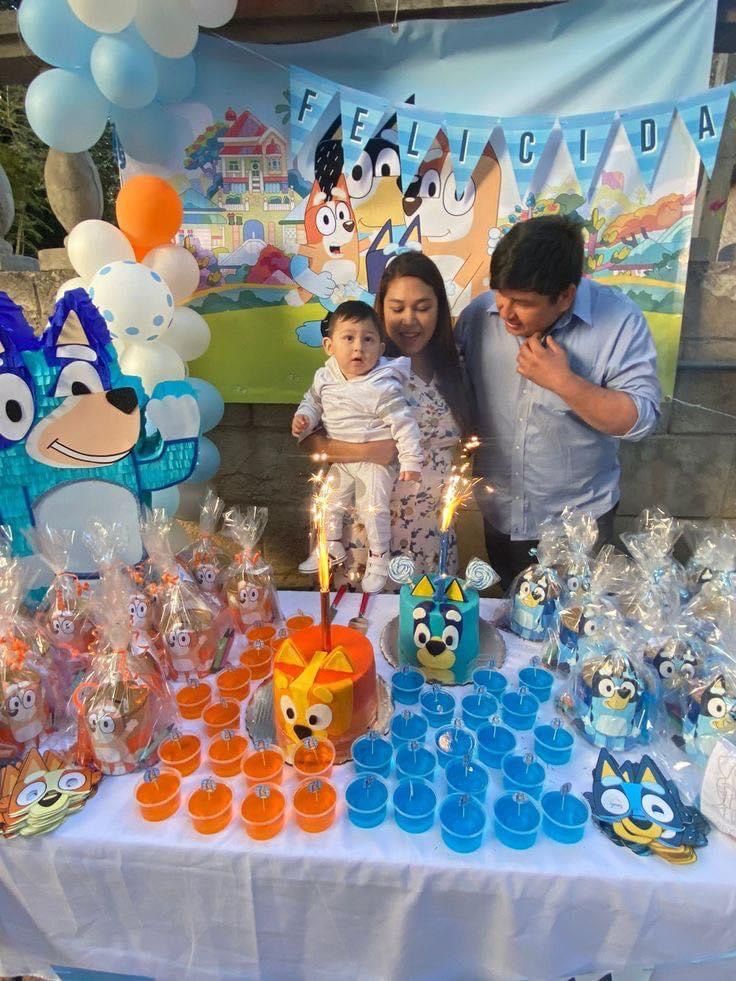 a man and woman standing next to a child at a table with cupcakes