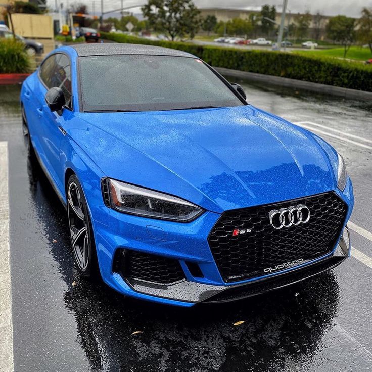 a blue car is parked in the rain