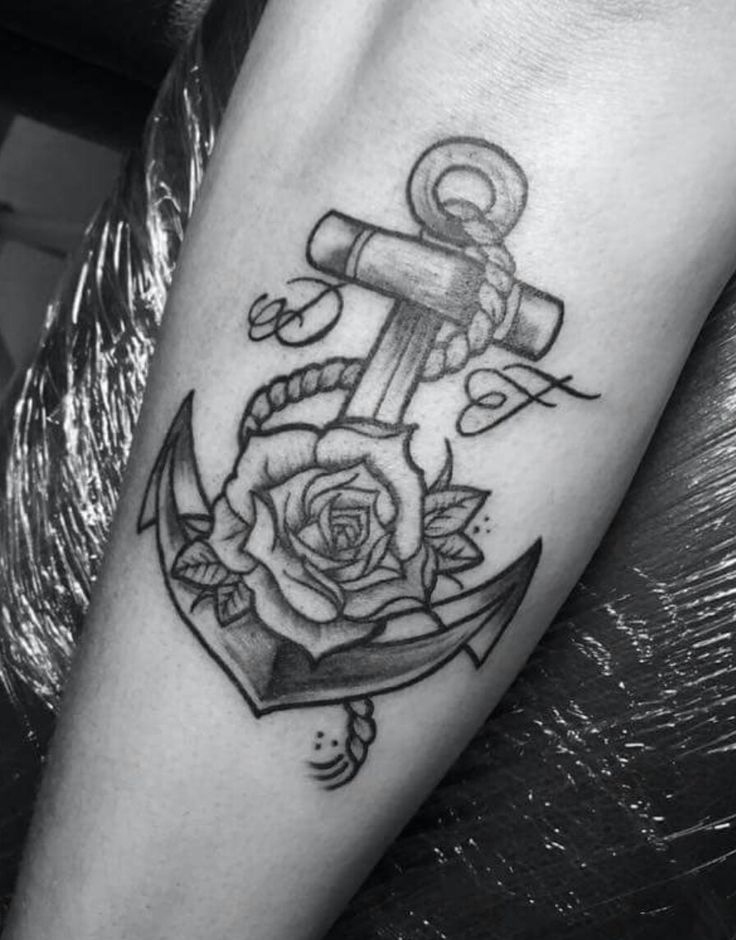 a black and white photo of an anchor with rose tattoo on the arm, done by person