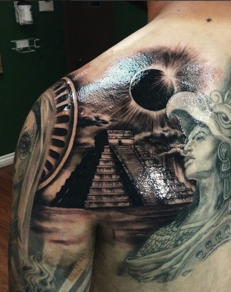 the back of a man's shoulder with tattoos on it and an egyptian statue